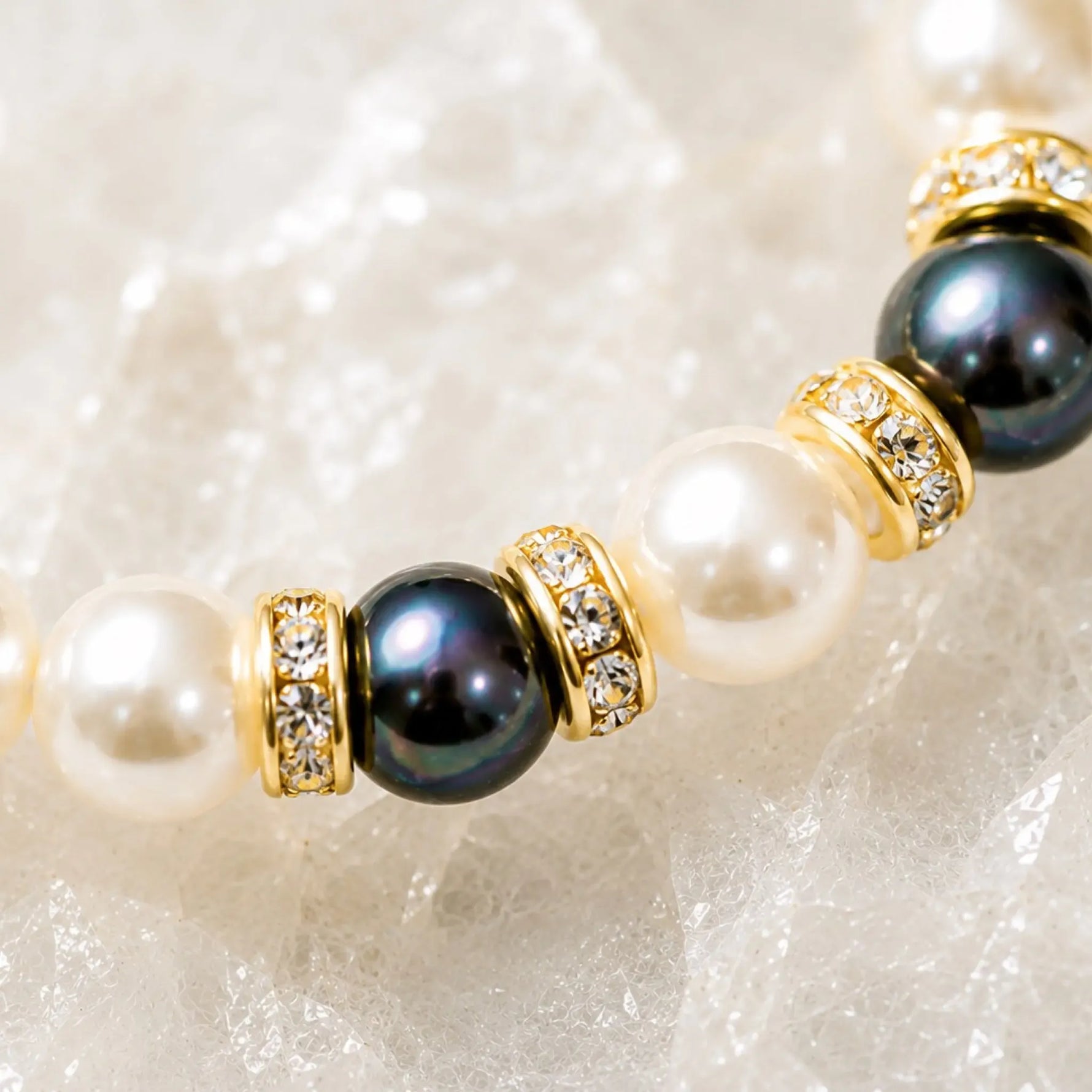 Macro detail of the Juanita Swarovski® Crystal Pearl bracelet featuring cream and dark grey Swarovski® Crystal Pearls, gold crystal rondelles, and handcrafted detailing.
