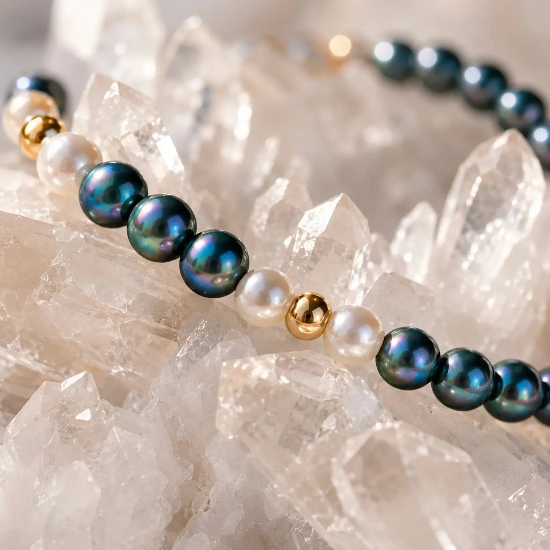 Luxury macro detail of the Kaia Swarovski® Crystal Pearl Bracelet highlighting 4 mm Tahitian Swarovski® Crystal Pearls, Moonlight Swarovski® Crystal Pearls, and 14k gold-filled accents resting on white quartz crystals.