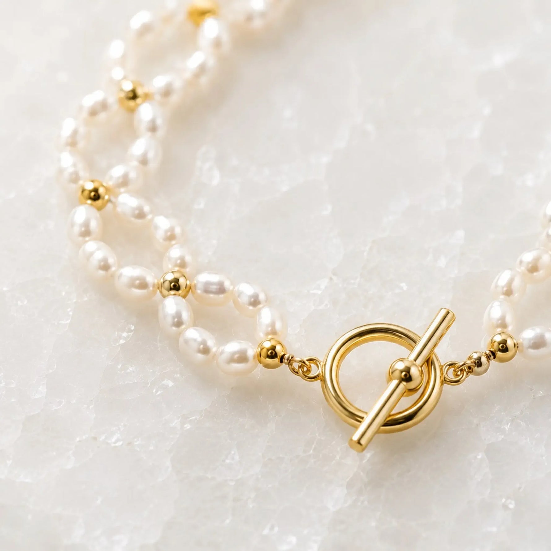 Macro detail of the Kailani Freshwater Pearl Necklace highlighting the handcrafted freshwater rice pearls, champagne gold spacer beads, and champagne gold toggle clasp.