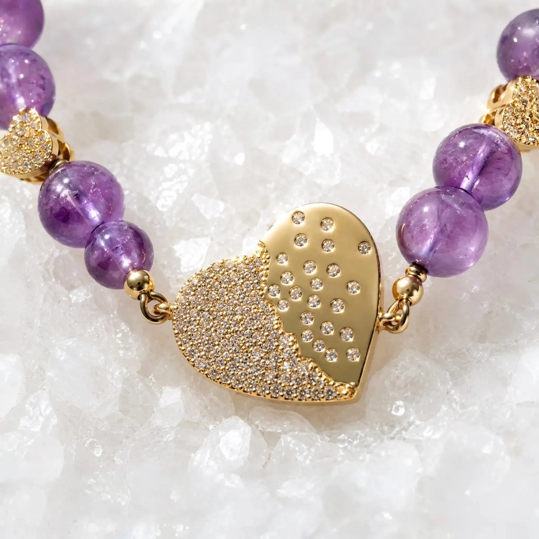 Macro detail of the Kalei bracelet's pavé heart connector with polished gold finish, cubic zirconia, and natural amethyst gemstones.