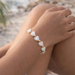 Kalila Mother of Pearl Heart Bracelet with gold-filled accent beads worn at a luxury beach destination, showcasing effortless elegance and vacation-ready sophistication.