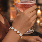 Kalila Mother of Pearl Heart Bracelet with gold accents worn during an elegant evening cocktail gathering, highlighting timeless feminine luxury and refined style.