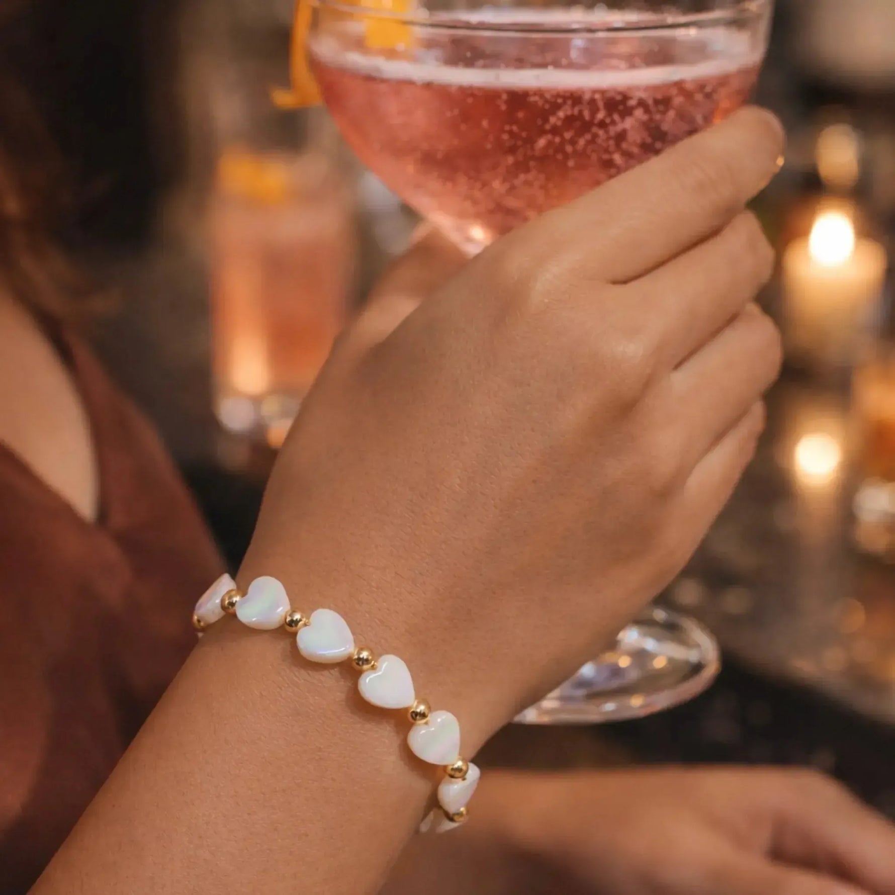 Kalila Mother of Pearl Heart Bracelet with gold accents worn during an elegant evening cocktail gathering, highlighting timeless feminine luxury and refined style.
