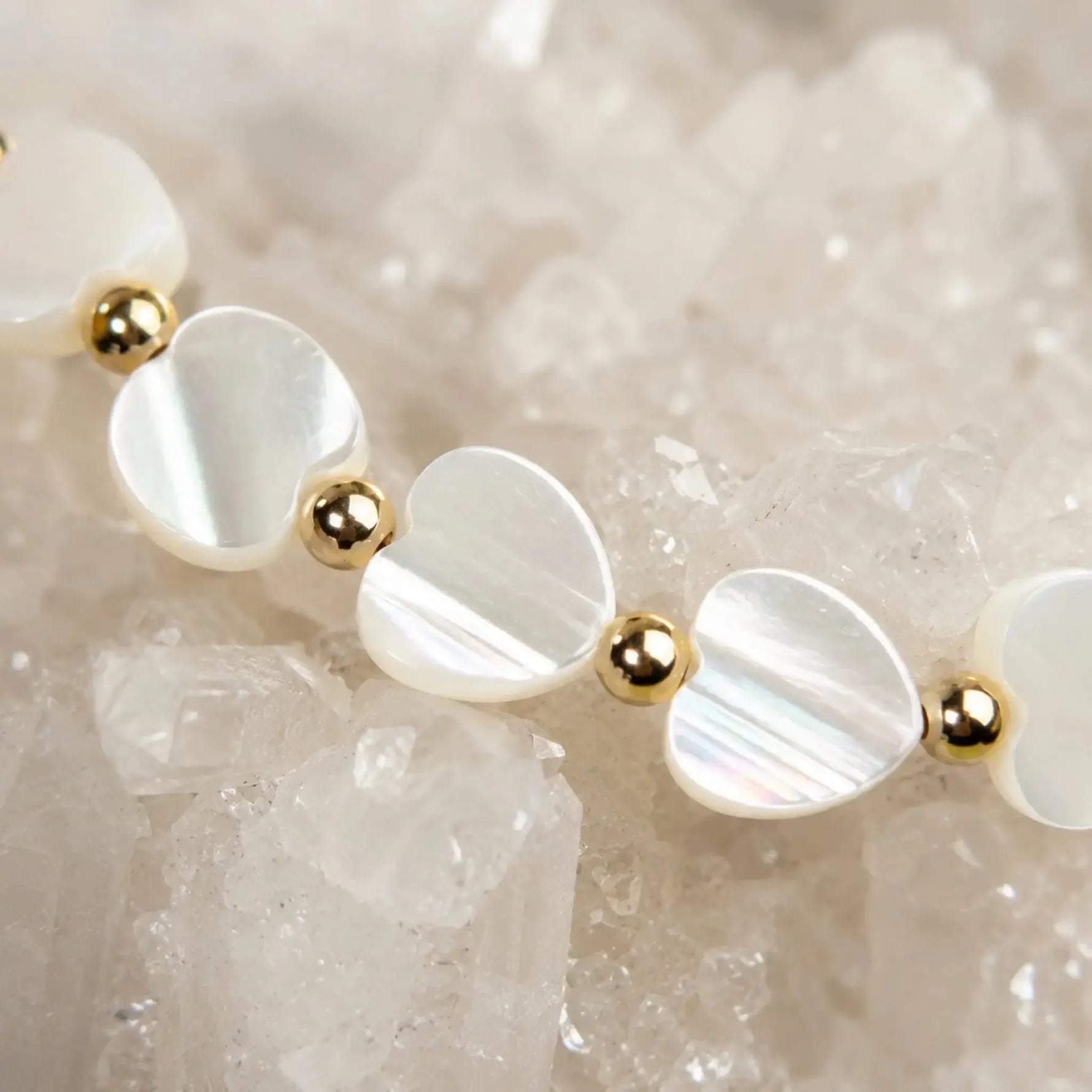 Macro detail of the Kalila Mother of Pearl Heart Bracelet featuring iridescent Mother of Pearl heart beads, polished 14k gold-filled beads, and sparkling quartz crystals.