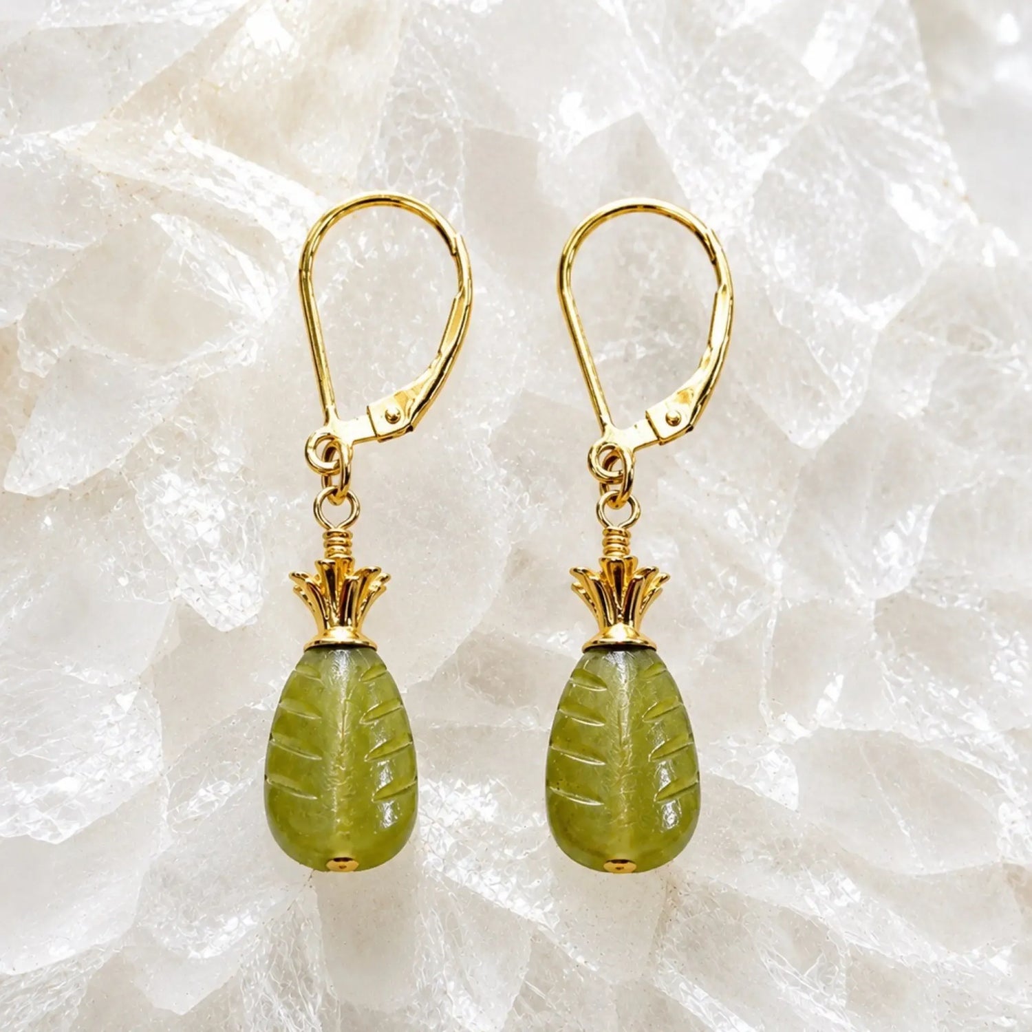Layla carved jade drop earrings with 14k gold accents displayed on a bright white crystal background, showcasing intricate jade carving and polished gold details.
