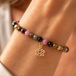 Close-up of the Layla rainbow tourmaline bracelet worn on a woman's wrist, showcasing colourful faceted tourmaline gemstones, polished gold accents, and lotus charm detail.