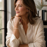 Woman wearing the Leilani Swarovski® Crystal Pearl Bracelet with an ivory silk blouse and cream cashmere wrap in a softly lit office setting, reflecting timeless professional elegance.