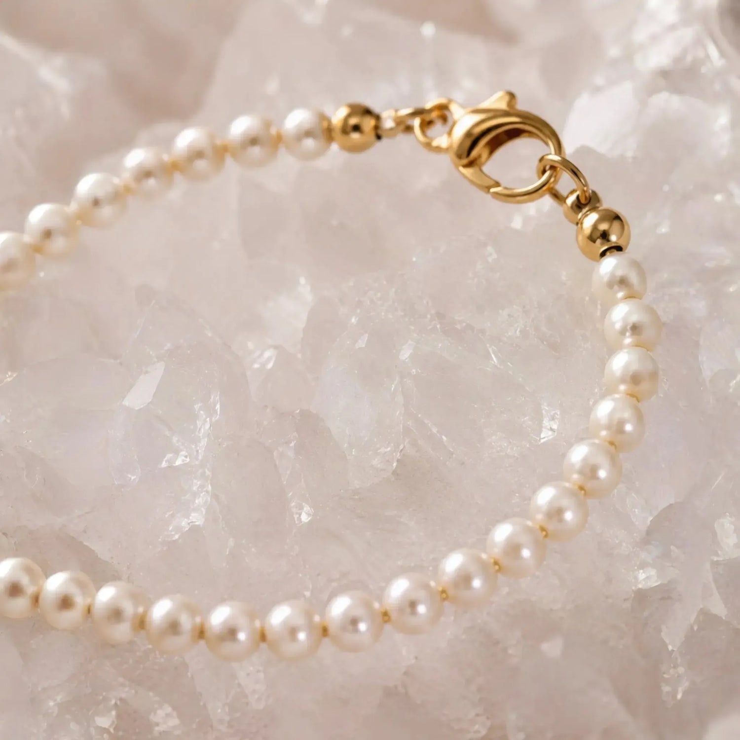 Macro detail of the Leilani Swarovski® Crystal Pearl Bracelet showcasing cream Swarovski® Crystal Pearls, polished gold clasp, and fine craftsmanship against luminous white quartz crystal.