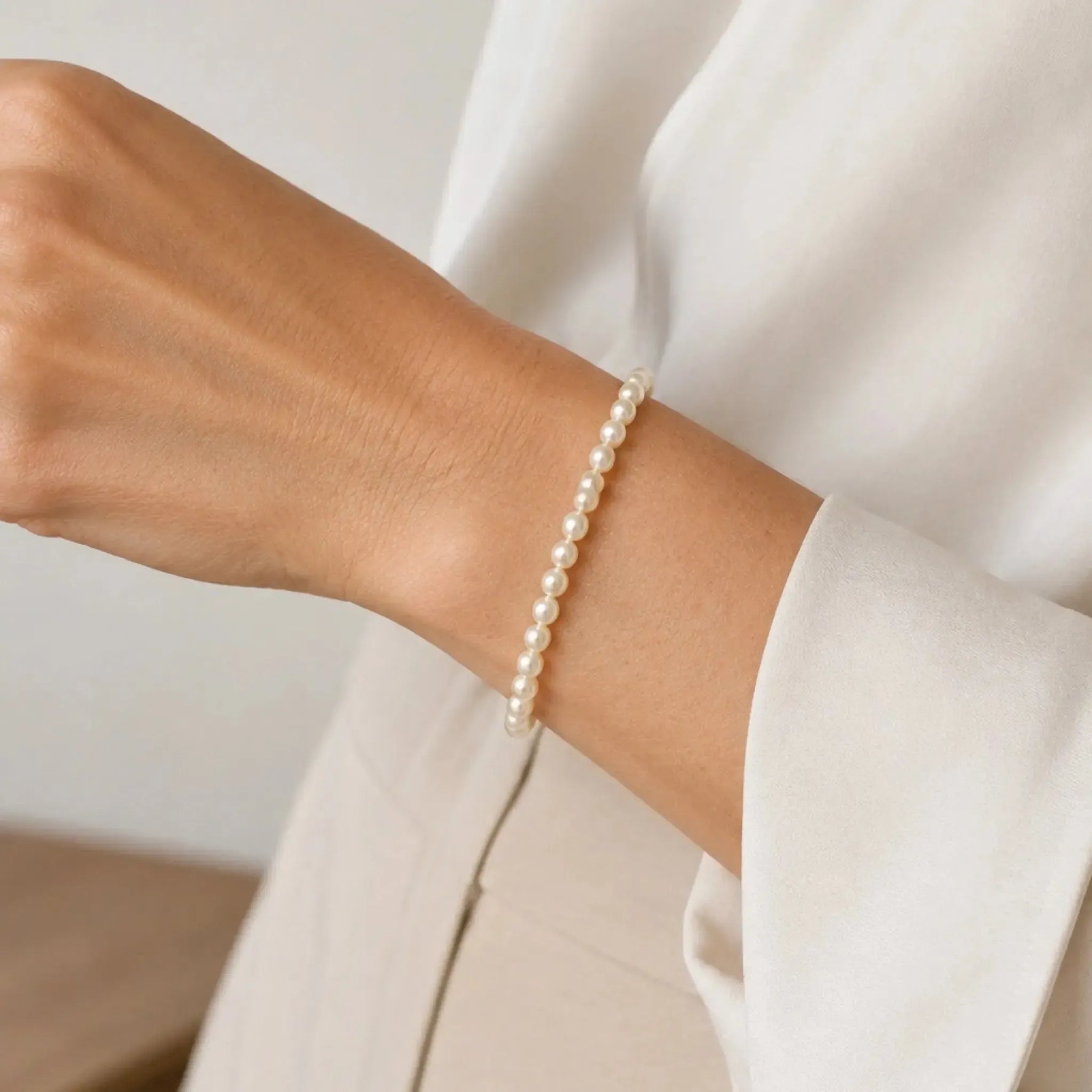 Leilani Swarovski® Crystal Pearl Bracelet worn on the wrist with an ivory blouse, illustrating the delicate scale, fit, and refined everyday elegance of the design.