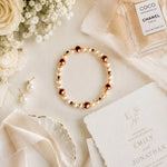 Meli Swarovski® Crystal Pearl Bracelet styled with pearl earrings, silk ribbon, wedding invitation, and bridal accessories in an elegant wedding flat lay.