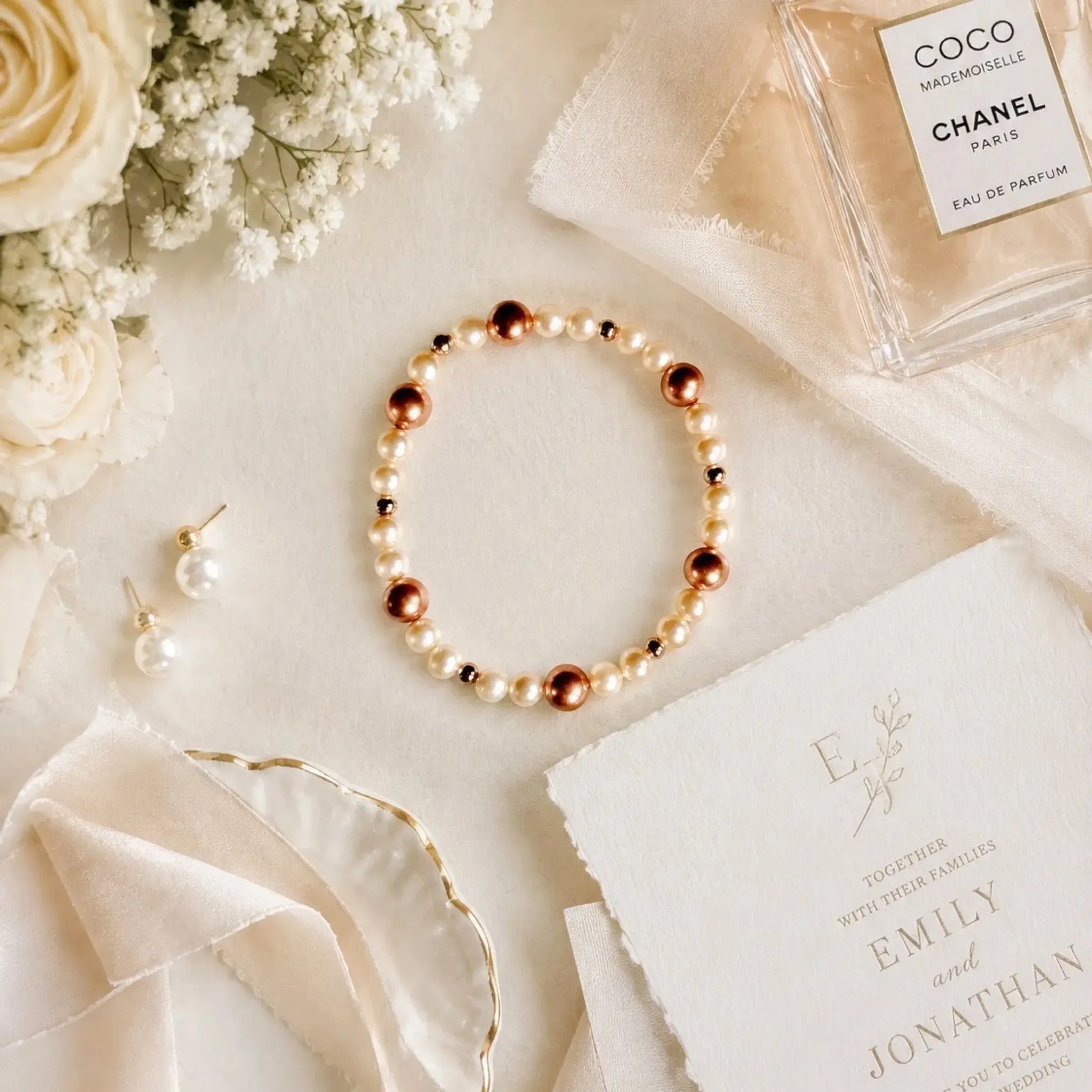 Meli Swarovski® Crystal Pearl Bracelet styled with pearl earrings, silk ribbon, wedding invitation, and bridal accessories in an elegant wedding flat lay.