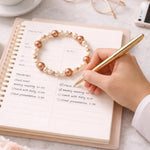 Meli Swarovski® Crystal Pearl Bracelet styled with a planner and gold pen, illustrating refined everyday elegance and professional versatility.