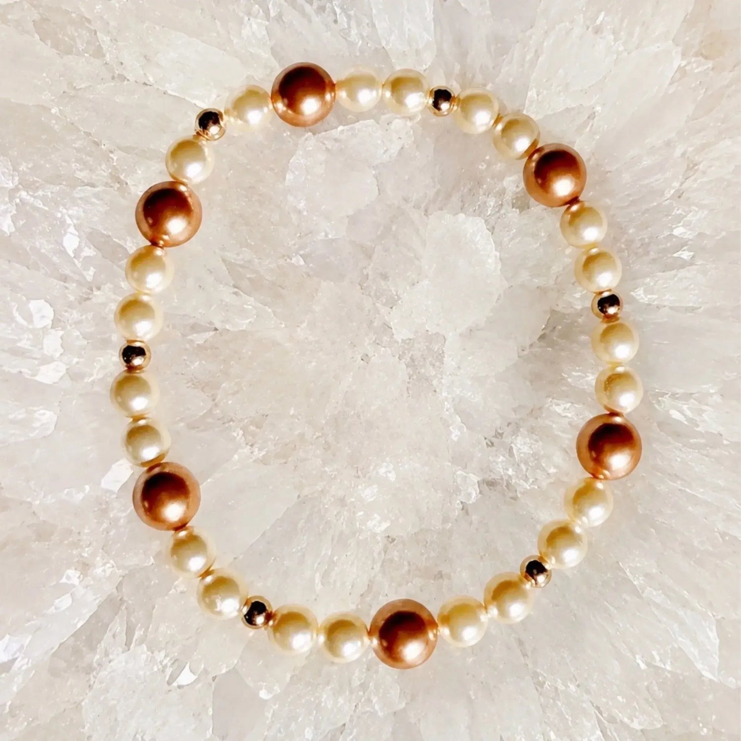Meli Swarovski® Crystal Pearl Bracelet featuring cream and rose gold Swarovski® Crystal Pearls with 14k gold-filled accent beads arranged on a white quartz crystal cluster.