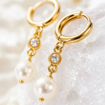 Macro close-up of Melia pearl huggie earrings highlighting the polished gold hoop, crystal setting, pearl attachment, and handcrafted craftsmanship.