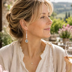 Woman wearing Mia Freshwater Pearl Earrings at an outdoor garden winery setting, featuring freshwater pearls and apple blossom details in a naturally elegant lifestyle scene.