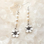 Mia Freshwater Pearl Earrings resting on luminous white quartz crystal, featuring genuine freshwater pearls, sterling silver ear wires, and detailed pewter apple blossom charms.