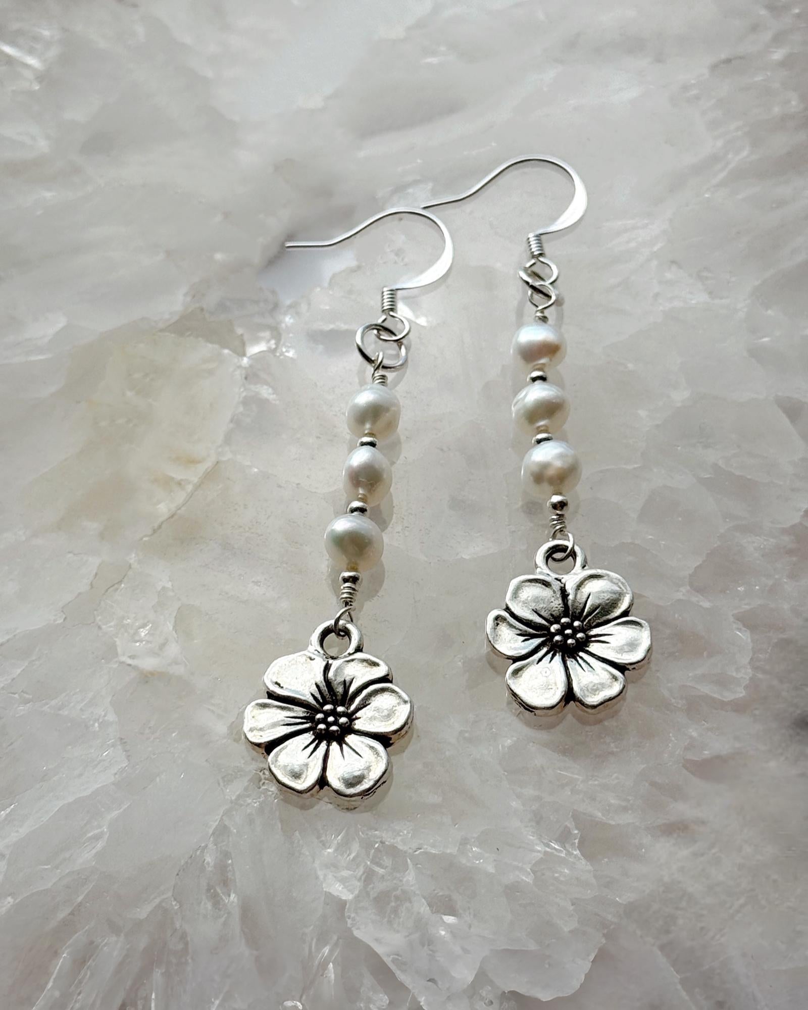 Carabella by Cheryl Mia Pearl & Apple Blossom Earrings with sterling silver and freshwater pearls displayed on a crystal background — handcrafted floral artisan jewelry.