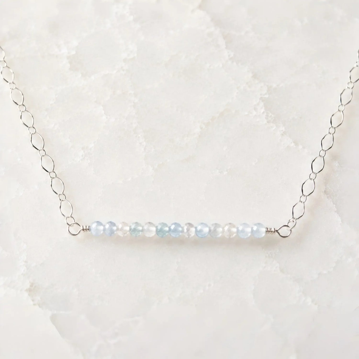 Morgan Bar Necklace featuring faceted morganite gemstones and sterling silver on a white quartz background.