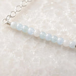 Close-up of faceted morganite gemstones and sterling silver wire wrapping on the Morgan Bar Necklace.