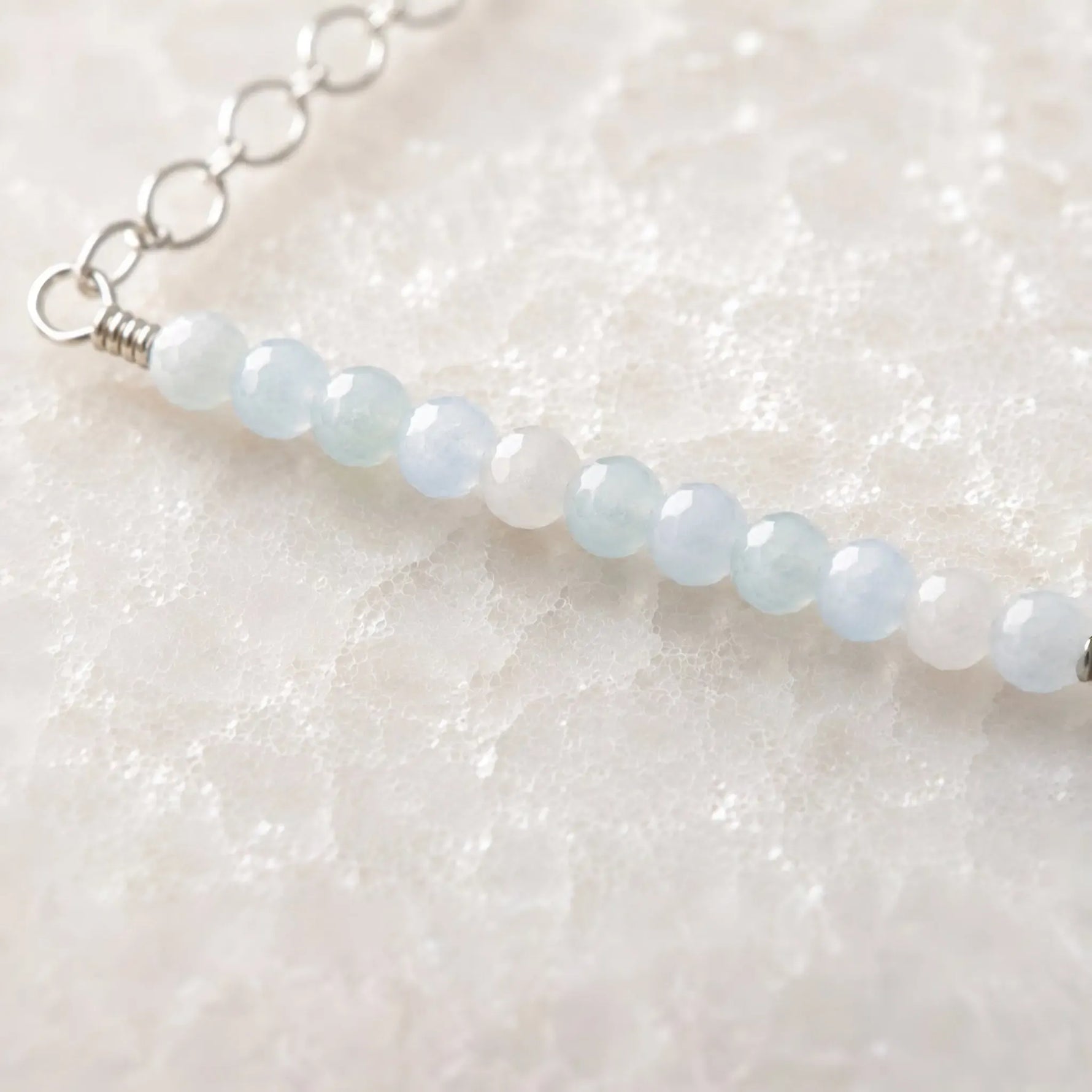 Close-up of faceted morganite gemstones and sterling silver wire wrapping on the Morgan Bar Necklace.