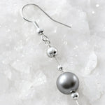 Macro detail of Natasha Swarovski® Crystal Pearl Earrings highlighting the sterling silver French hook, faceted silver bead, fine wire, and luminous dark grey Swarovski® Crystal Pearl.