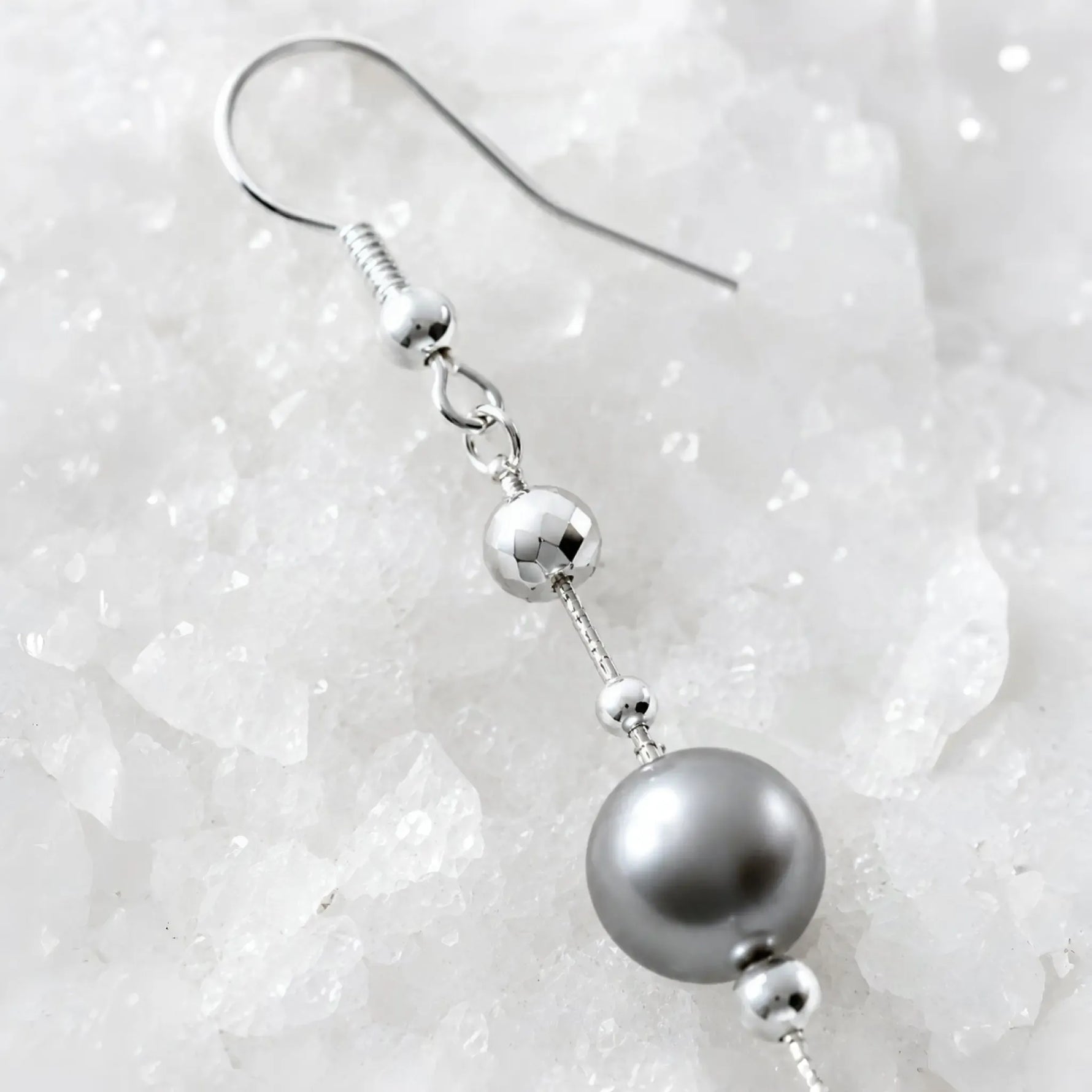 Macro detail of Natasha Swarovski® Crystal Pearl Earrings highlighting the sterling silver French hook, faceted silver bead, fine wire, and luminous dark grey Swarovski® Crystal Pearl.