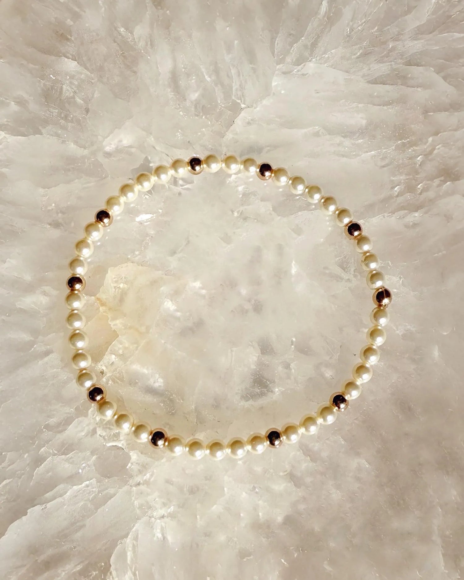 Noelani Cream Pearl & Gold Bracelet flat lay on luminous stone surface