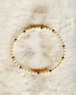 Close view of Noelani cream pearl bracelet with gold accents on natural stone