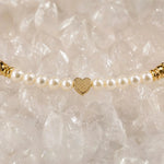Macro detail of the Pandora Swarovski® Crystal Pearl Bracelet showcasing the textured gold heart centerpiece framed by cream Swarovski® Crystal Pearls atop luminous white quartz crystal.