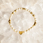 Pandora Swarovski® Crystal Pearl and gold heart bracelet arranged on luminous white quartz crystal, featuring cream Swarovski® Crystal Pearls, faceted gold hematite beads, and textured gold heart centerpiece.