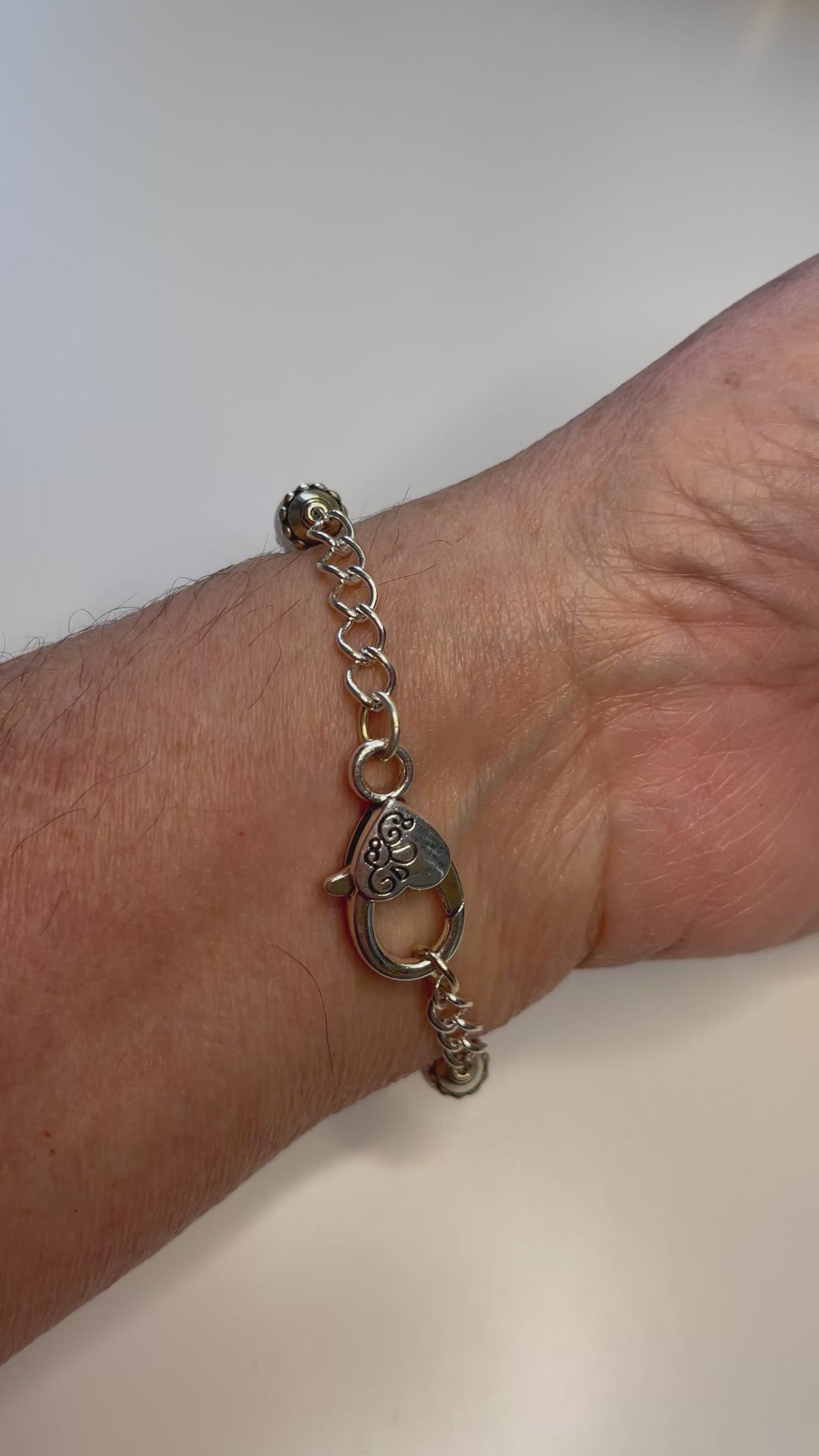 Video of a model wearing the Venus Rose Quartz Bracelet, highlighting the soft pink rose quartz gemstones, pewter bead caps, silver-plated curb chain, and heart-shaped clasp. Handcrafted in Canada by Carabella by Cheryl.