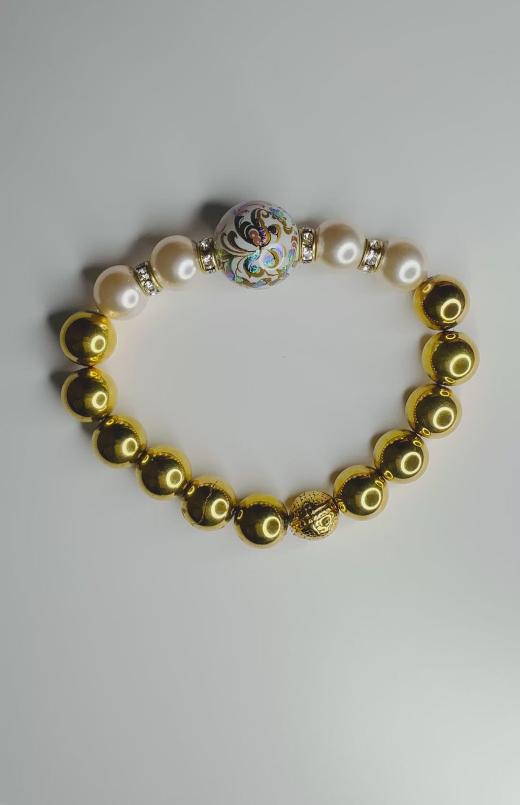 Video showing a close-up of the Imperial Blossom Bracelet’s Japanese Tensha bead with floral artwork, paired with Austrian pearls and gold-plated hematite.