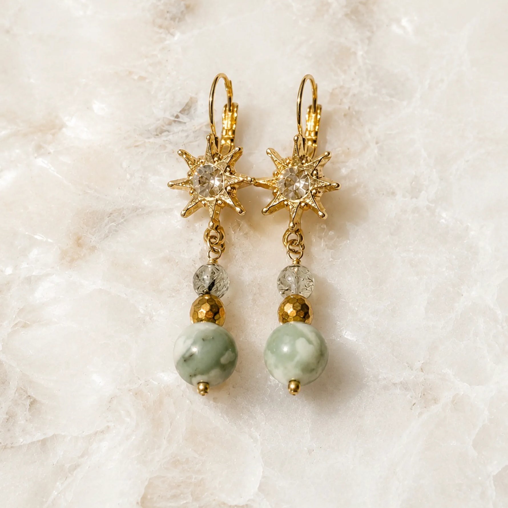 Quianna handcrafted gold drop earrings featuring genuine lucky jade, green tourmalinated quartz, Austrian crystal, and gold-plated leverback earrings displayed on the Carabella signature white quartz background.