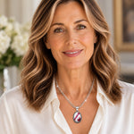 Woman wearing the Sabine Tourmaline Pendant Necklace with an ivory blouse, showcasing the raspberry pink and white gemstone pendant and silver-tone chain.