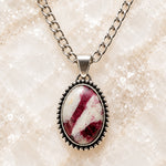 Close-up of the Sabine Tourmaline Necklace showing the natural raspberry pink and creamy white gemstone pattern, polished silver-tone setting and decorative beaded border.