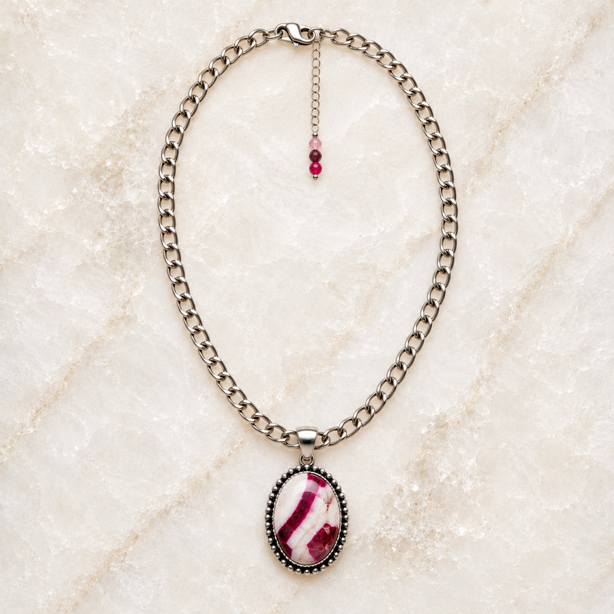 Sabine handcrafted tourmaline pendant necklace featuring a raspberry, blush and creamy-white gemstone on a polished silver-plated stainless steel chain, with a delicate three-tourmaline extender, displayed on white quartz.