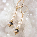 Serenity Swarovski® Crystal Pearl earrings with dark grey accent pearls and 14k gold-filled leverbacks displayed on a white quartz crystal cluster in a luxury macro close-up