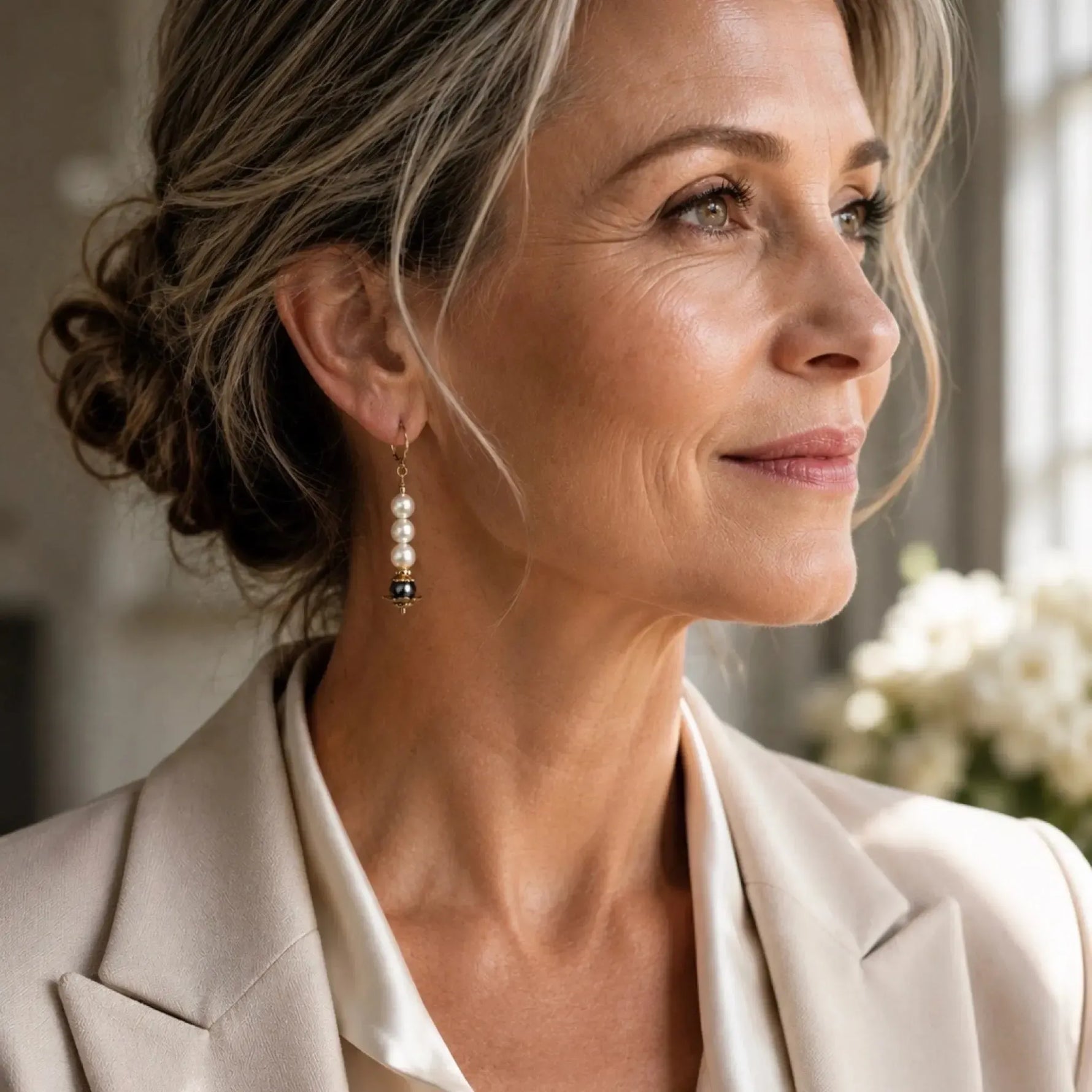 Elegant wearing Serenity Swarovski® Crystal Pearl earrings with an ivory silk blouse and tailored blazer in natural window light