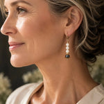 Close-up profile of a woman wearing Serenity Swarovski® Crystal Pearl Earrings featuring cream Swarovski® Crystal Pearls, a dark grey Swarovski® Crystal Pearl accent, and 14k gold-filled leverback ear wires with gold-plated bead caps.