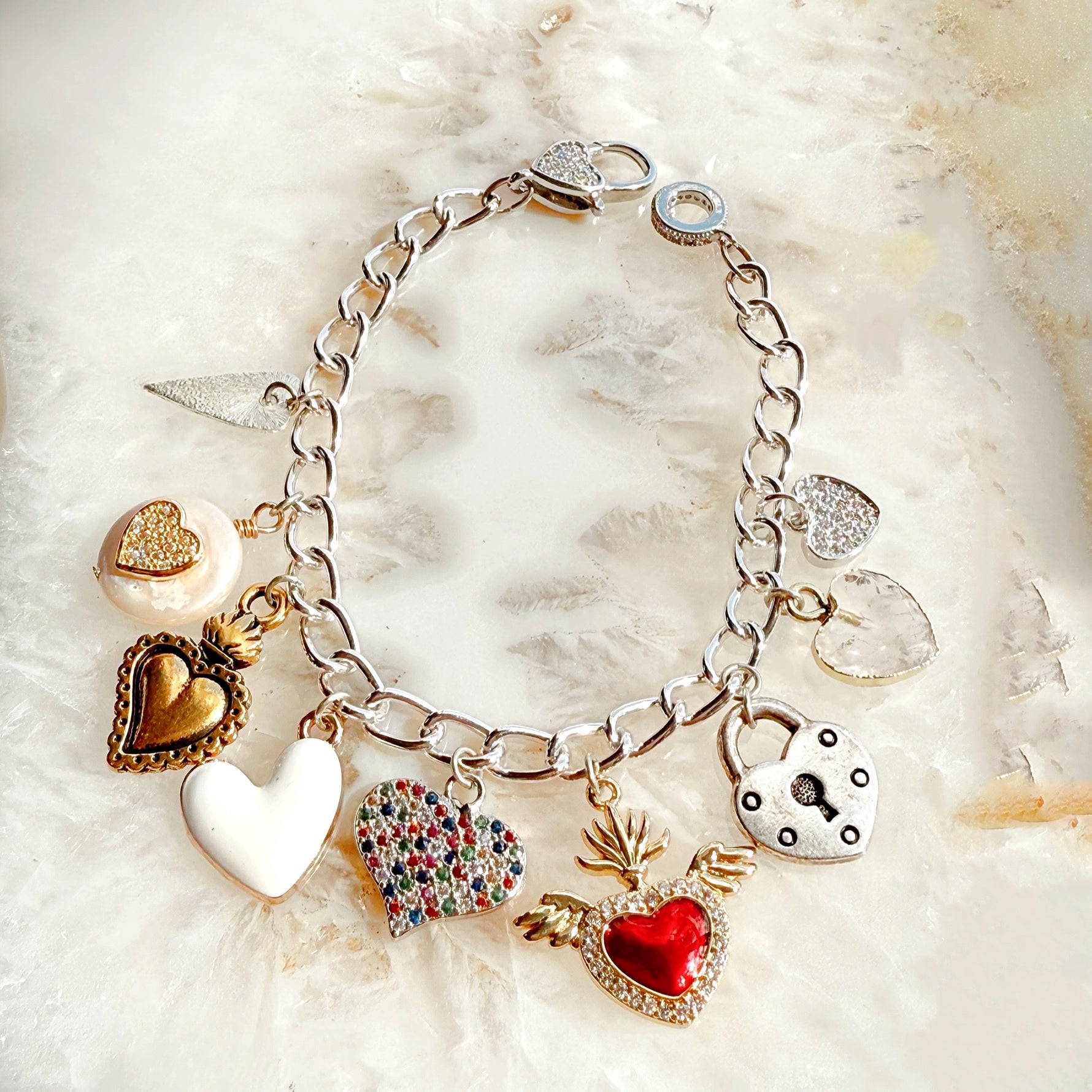 Esme charm bracelet styled flat lay showcasing multi-metal heart charms for everyday luxury wear.