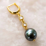 Luxury macro of a Tahitian South Sea black pearl earring highlighting natural pearl overtones, crystal bezels, gold wire wrapping, and handcrafted construction.