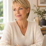 Woman wearing Tahitian South Sea black pearl drop earrings with crystal accents while working in a bright office, styled with an ivory cashmere sweater for an elegant everyday look.