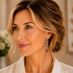 Woman wearing handcrafted sterling silver Tiger's Eye maple leaf earrings with an ivory blouse in soft natural light.