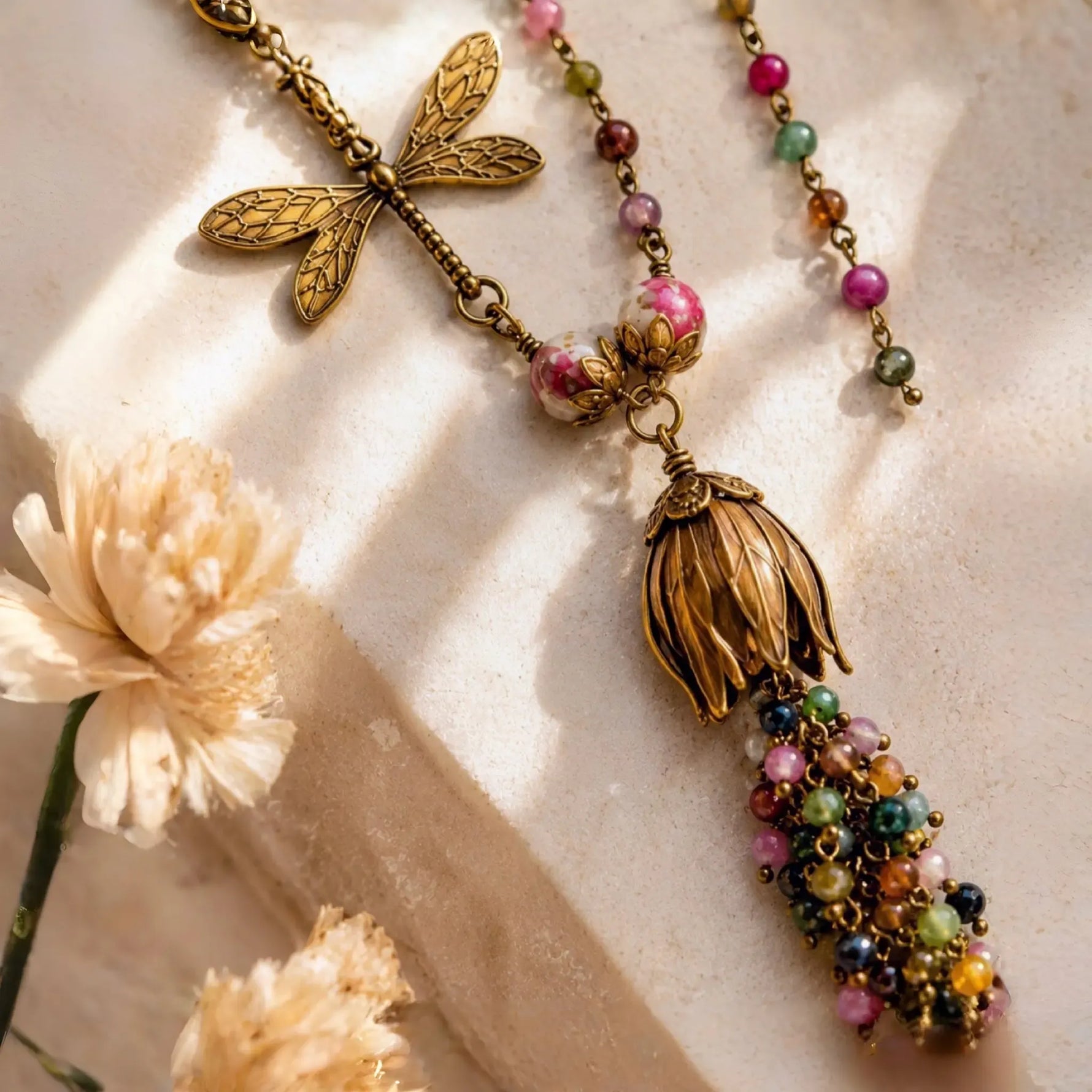 Close-up of the Tulipe necklace showcasing the detailed brass dragonfly charm, sculptural tulip focal, and colourful watermelon tourmaline gemstones