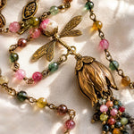Macro detail of the Tulipe necklace highlighting faceted watermelon tourmaline gemstones, hand-wrapped wire construction, brass dragonfly charm, and tulip focal.