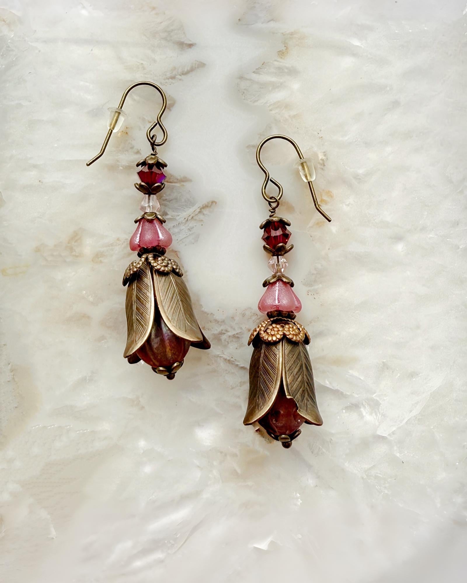 Tulipe Garden Reverie Earrings crafted in Vintaj brass with pink Czech glass blossoms and Austrian crystals, shown on a white crystal background — Carabella by Cheryl.