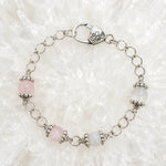 Venus Bracelet featuring rose quartz and moonstone gemstones with sterling silver accents arranged on luminous white quartz crystal.