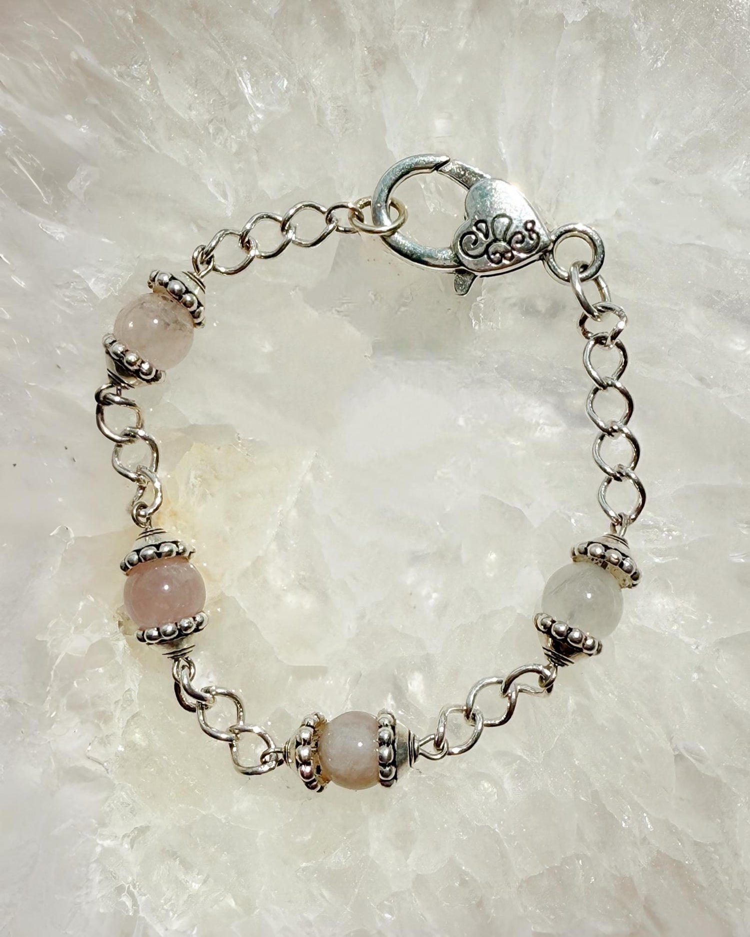 Close-up of the Venus Rose Quartz Bracelet featuring natural rose quartz gemstones, pewter bead caps, and a silver-plated curb chain with a heart clasp. Handcrafted in Canada by Carabella by Cheryl.