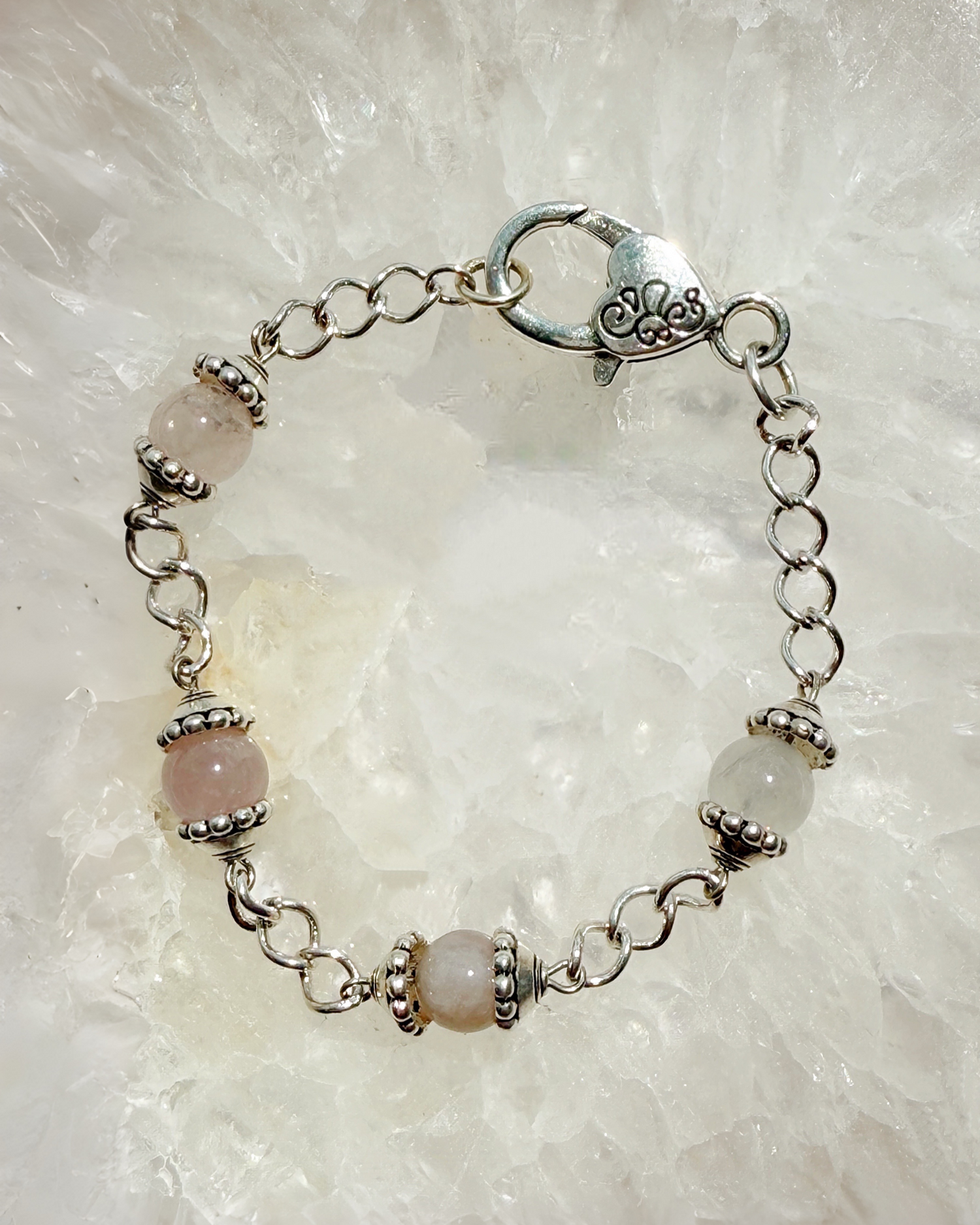 Close-up of the Venus Rose Quartz Bracelet featuring natural rose quartz gemstones, pewter bead caps, and a silver-plated curb chain with a heart clasp. Handcrafted in Canada by Carabella by Cheryl.