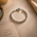 Zoe sterling silver Byzantine weave bracelet styled for an elegant evening on a marble surface with candlelight and refined accessories.
